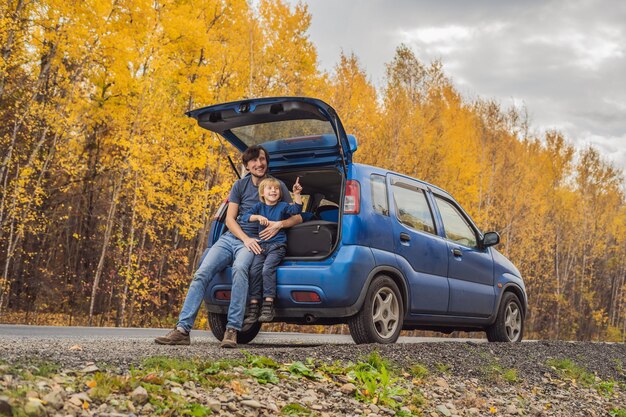Dad and son are resting on the side of the road on a road trip Road trip with children concept