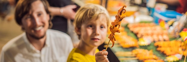 Dad and son are tourists on walking street asian food market banner long format