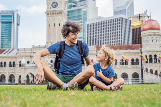 Dad and son on background of Merdeka square and Sultan Abdul Samad Building. Traveling with children concept