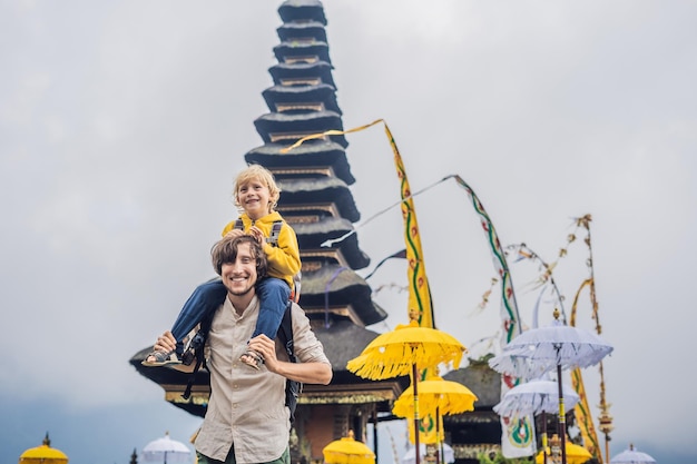 Dad and son in the background of pura ulun danu bratan bali hindu temple surrounded by flowers on