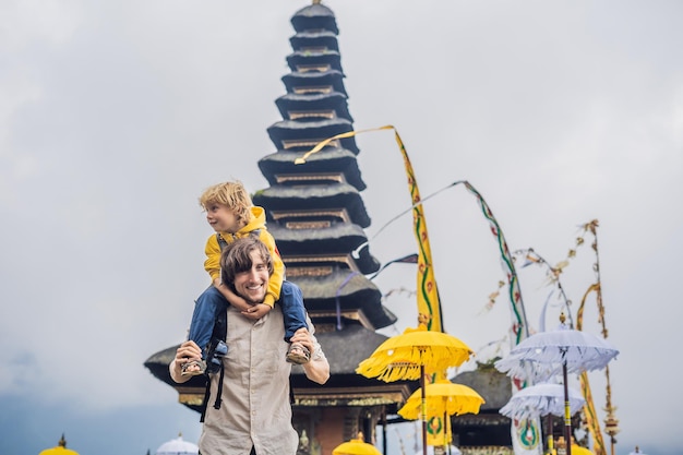 Dad and son in the background of pura ulun danu bratan bali hindu temple surrounded by flowers on