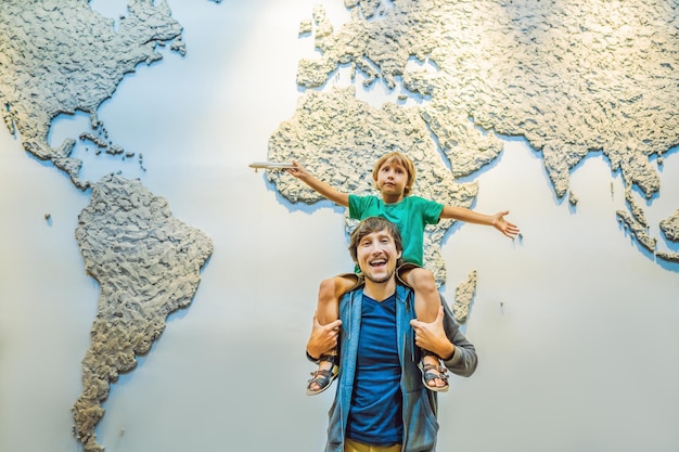 Dad and son on the background of a world map with an airplane\
in his hands travel concept