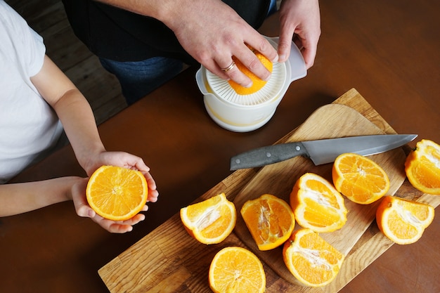 Photo dad and son make orange juice squeeze from fresh oranges