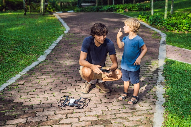Dad and son playing with drone man and boy playing with flying drone in sunny autumn garden happy