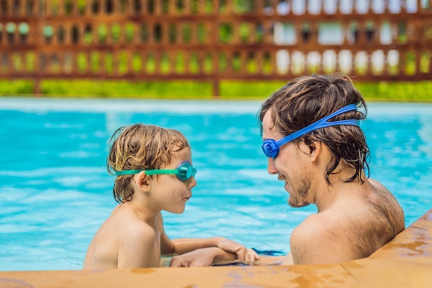 水泳ゴーグルの父と息子はプールで楽しんでいます