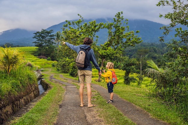 Dad and son travelers on Beautiful Jatiluwih Rice Terraces against the background of famous volcanoes in Bali, Indonesia Traveling with children concept