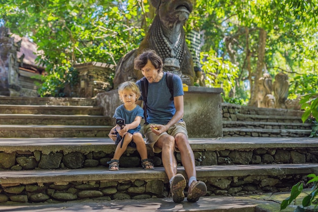 Dad and son travelers discovering Ubud forest in Monkey forest, Bali Indonesia. Traveling with children concept. Videoblog, Selfie..