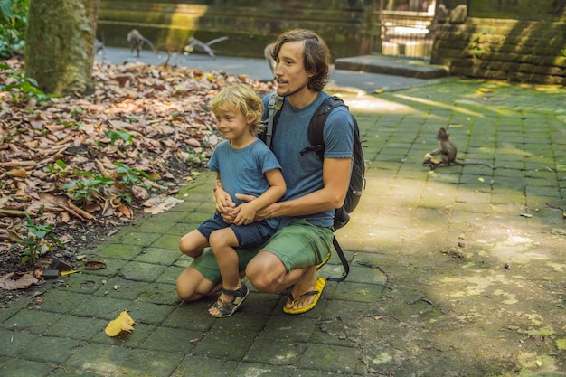 Dad and son travelers discovering Ubud forest in Monkey forest, Bali Indonesia. Traveling with children concept.