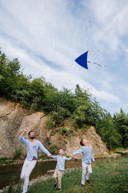 Foto papà e figli che corrono con l'aquilone sul prato