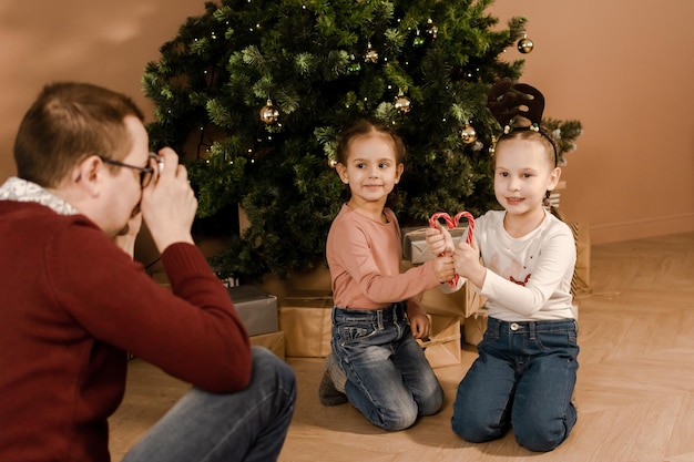 写真 お父さんはクリスマスツリーで彼の娘の写真を撮ります