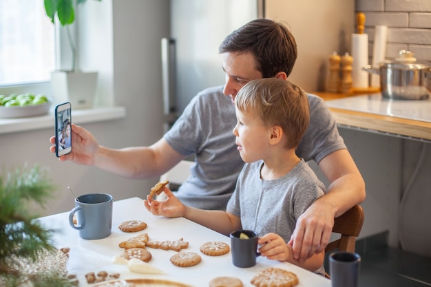 Dad takes pictures of topview as daughter and son decorate gingerbread with sugar icing stylish home...