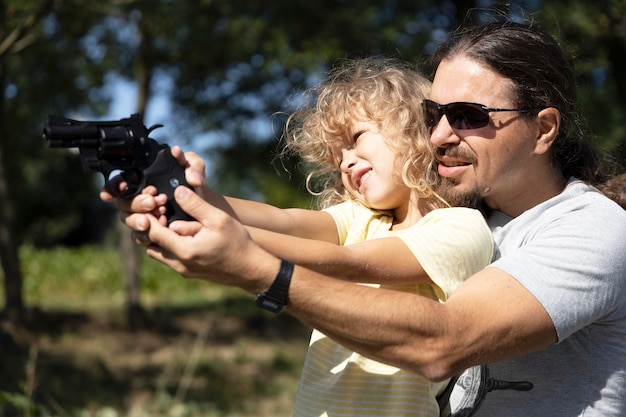 Foto il padre insegna alla figlia a sparare con una pistola ad aria compressa
