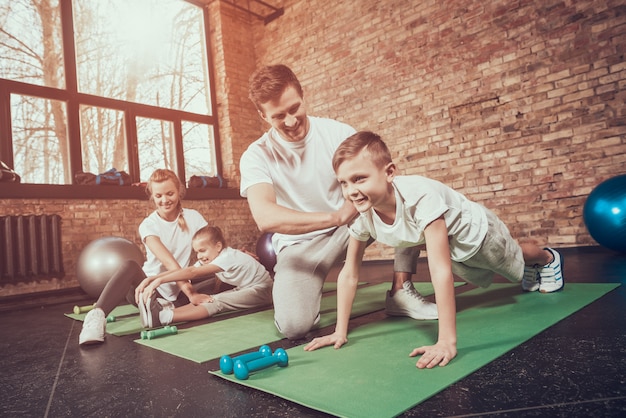 Dad teaches son to push up son in gym.