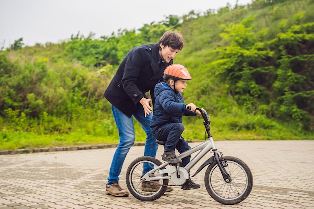 dad teaches son to ride a bike in the park.