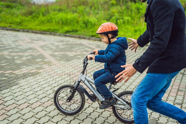 お父さんは息子に公園で自転車に乗るように教えます。