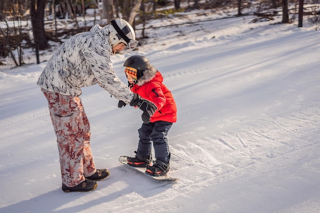 Dad teaches son snowboarding Activities for children in winter Children's winter sport Lifestyle