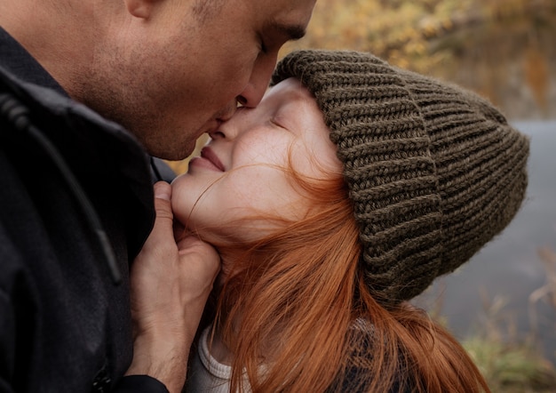 Photo dad on a walk kisses his red daughter in the nose.