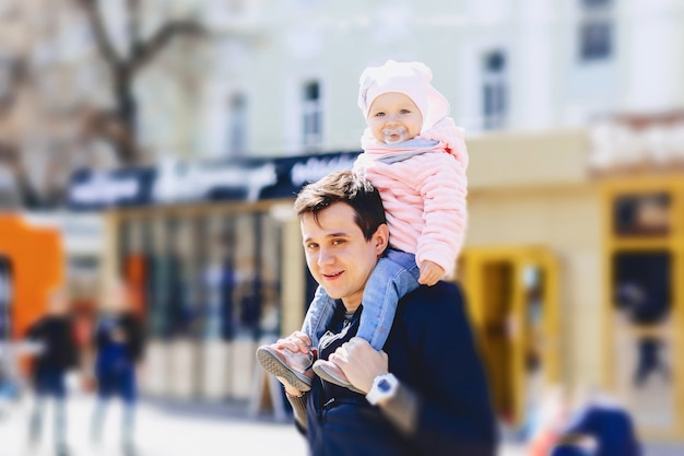 Dad with baby at shoulders walk on street