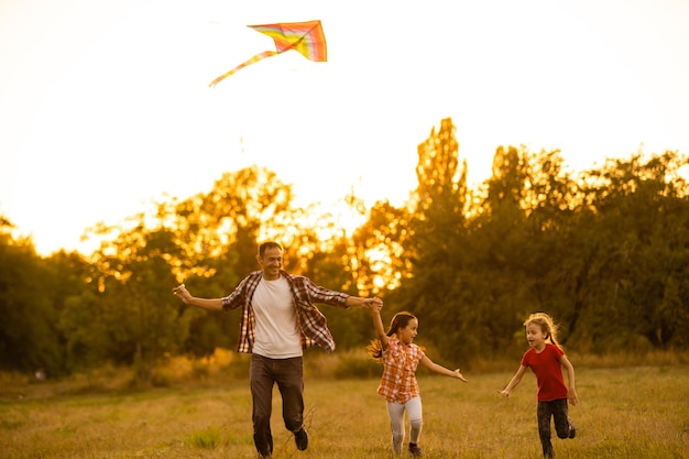幼い娘と一緒のお父さんが野原で凧を放ちました