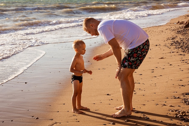 Papà con suo figlio sulla spiaggia giovane padre caucasico con bambino felice in vacanza in una giornata di sole