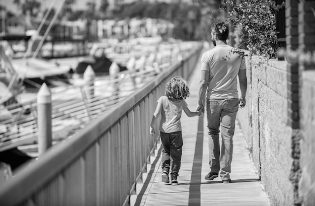 Dad with kid on summer day parenting and fatherhood back view father and son walk outdoor family value childhood and parenthood parent with small child boy