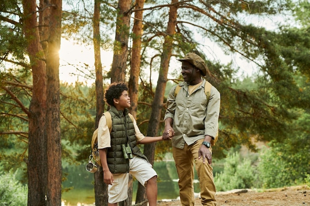 Dad with son hiking together in the forest during summer vacation