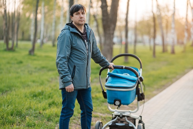 Photo dad with stroller walking in the park