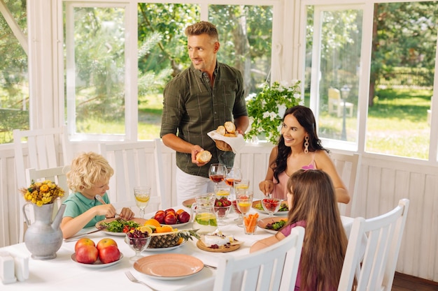 Daddy bringing some bread while having family lunch outside