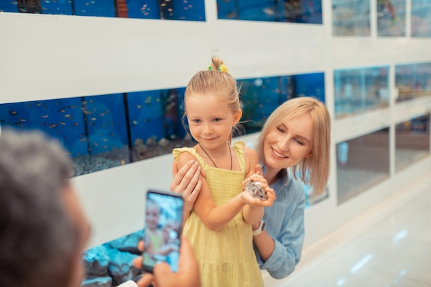 Daddy taking photo of daughter holding little hamster in hands