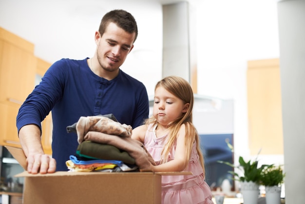 Daddys little helper A father and daughter packing clothes in a donations box