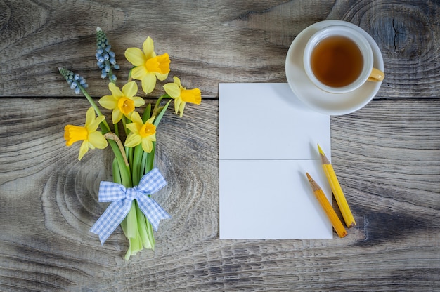 Daffodils and muscari flowers with card and cup of tea