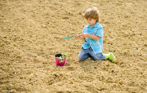 Dag van de aarde Eco leven zomer boerderij ecologie leven eco boerderij mens en natuur gelukkig kind zaaien op rijke grond Lente seizoen klein kind een bloem planten biologische boerderij plantage in een kas