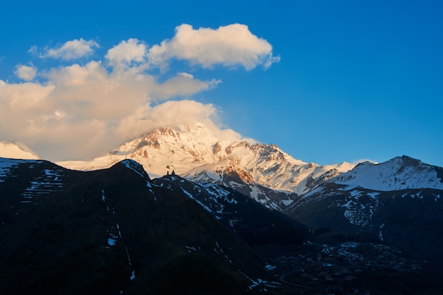 Dageraad in de bergen. De zonnestralen vallen op de top van de berg Kazbek. Een inspirerende ochtend voor de reiziger