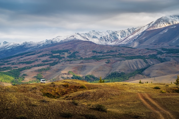 Dageraad in de Chuy-vallei, een toeristische minibus op een veldweg op een heuvel. Rusland, berg Altai