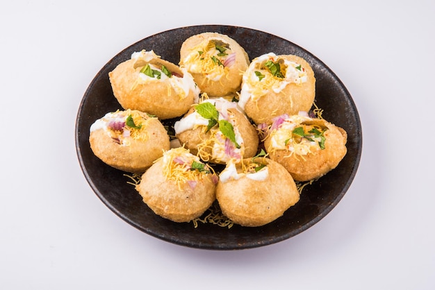 Dahi puri is een snack die populair is in de staat maharashtra, india. dit gerecht valt onder de categorie chat. geserveerd in een rond bord op een kleurrijke of houten ondergrond. selectieve focus