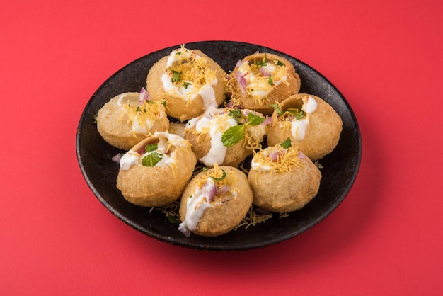 Dahi puri è uno snack popolare nello stato del maharashtra, in india. questo piatto rientra nella categoria chat. servito in un piatto rotondo su sfondo colorato o in legno. messa a fuoco selettiva