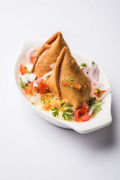 Dahi Samosa or samosa is a popular North indian snack dipped in curd, favourite tea time junk food served with tamarind and mint chutney or tomato ketchup and green fried chilli