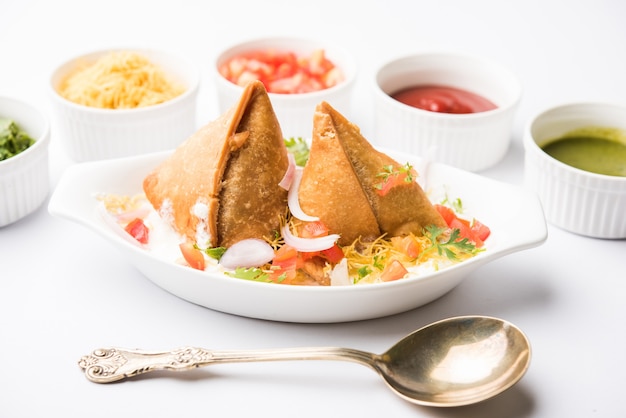 Dahi Samosa or samosa is a popular North indian snack dipped in curd, favourite tea time junk food served with tamarind and mint chutney or tomato ketchup and green fried chilli