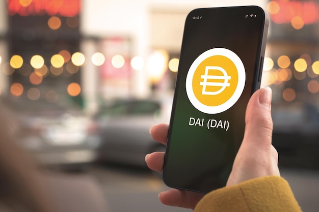 DAI cryptocurrency-symbool, logo. Zakelijk en financieel concept. Hand met smartphone, scherm met crypto icoon close-up