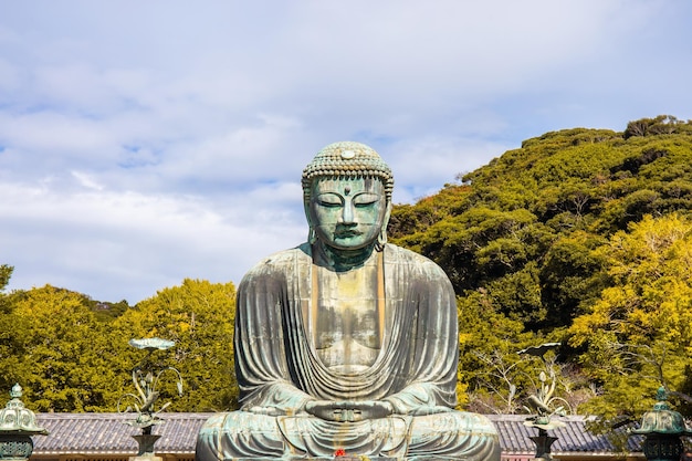 Foto daibutsu of grote boeddha van kamakura in kotokuin tempel in kanagawa prefectuur japan met bladeren die van kleur veranderen het is een belangrijk mijlpaal en een populaire bestemming voor toeristen en pelgrims