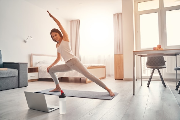 Daily activity. Delighted woman expressing positivity while doing sport in the morning at home