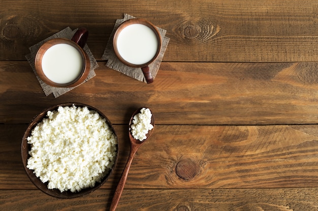 Молочные продукты, творог и молоко в деревянной посуде, вид сверху на деревянных