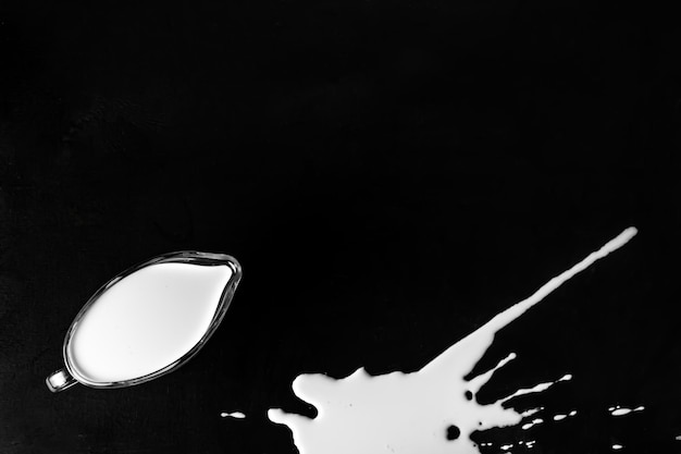 Dairy products cream and spilled milk on a black wooden background. copy space, place for text. raw natural food top view selected focus