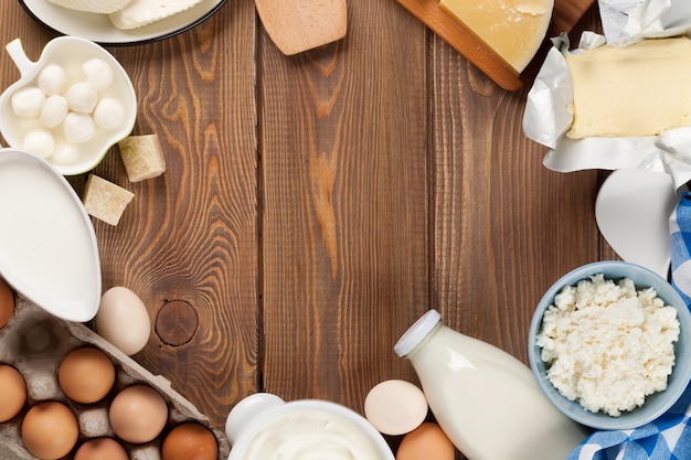 Dairy products on wooden table. Milk, cheese, egg, curd cheese and butter. Top view with copy space