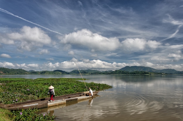 DAK LAK- VIET NAM: Group of Asian farmer go to work by row boat on Lak lake in autumn time 