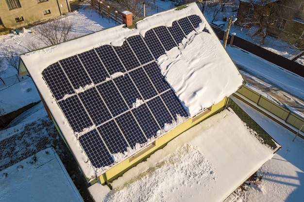 Dak van het huis bedekt met zonnepanelen in de winter met sneeuw erop. energie-efficiëntie en onderhoudsconcept.