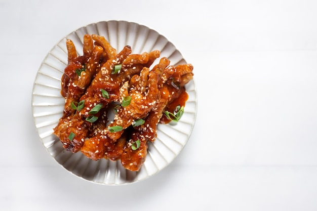 Dakbal or Maeun Dakbal is Spicy Chicken Feet, Korean Food Style served with sesame seeds and Kimchi.