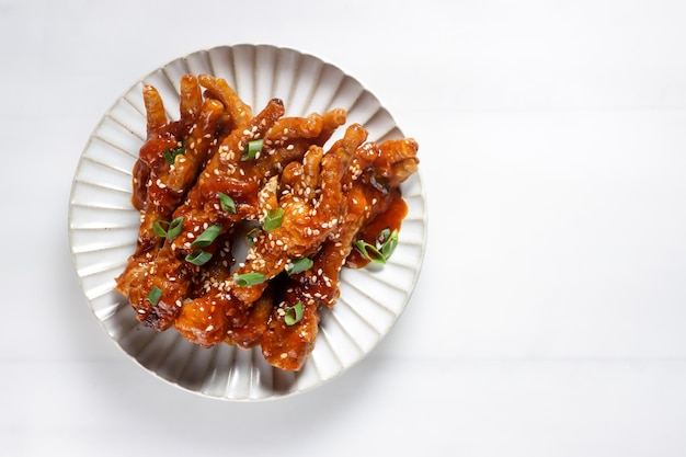 Dakbal of Maeun Dakbal is Spicy Chicken Feet, Korean Food Style geserveerd met sesamzaadjes en Kimchi.