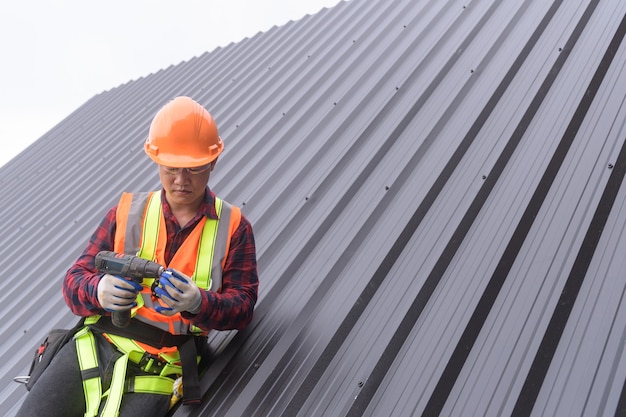 Foto dakdekker bouwvakker installeert nieuw dak, dakbedekkingsgereedschap, elektrische boor gebruikt op nieuwe daken met metalen plaat.