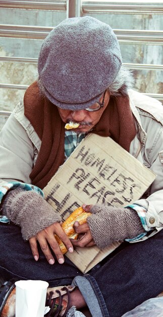 Dakloze man die brood eet op straat.